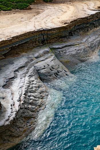 Aerial view of the rugged rocky coastline with distinct layered stone formations meeting the turquoise sea in Corfu Ionian Islands Greece. Aerial view of the rugged rocky coastline with distinct layered stone formations meeting the turquoise sea in Corfu Ionian Islands Greece.