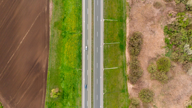 Aerial view of a straight highway cutting through a vivid landscape of freshly tilled brown fields vibrant green meadows and dry fields Sremska Mitrovica Vojvodina Serbia. Aerial view of a straight highway cutting through a vivid landscape of freshly tilled brown fields vibrant green meadows and dry fields Sremska Mitrovica Vojvodina Serbia.