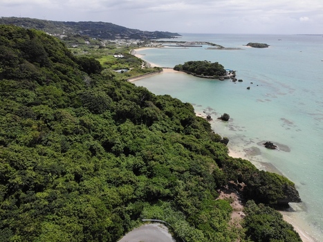 Aerial view of the Hyakume coastline featuring emerald green waters a white sandy beach and dense lush greenery in Nanjo Okinawa Japan. Aerial view of the Hyakume coastline featuring emerald green waters a white sandy beach and dense lush greenery in Nanjo Okinawa Japan.