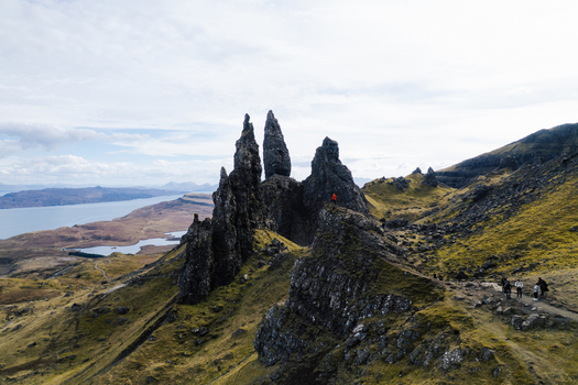 Aerial view of The Storr a dramatic rock formation on the Isle of Skye with rugged green slopes rocky cliffs and a distant coastline in Portree Scotland United Kingdom. Aerial view of The Storr a dramatic rock formation on the Isle of Skye with rugged green slopes rocky cliffs and a distant coastline in Portree Scotland United Kingdom.
