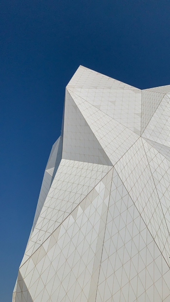 View of the geometric white facade of Ferrari World Yas Island against a clear blue sky Abu Dhabi Abu Dhabi United Arab Emirates. View of the geometric white facade of Ferrari World Yas Island against a clear blue sky Abu Dhabi Abu Dhabi United Arab Emirates.