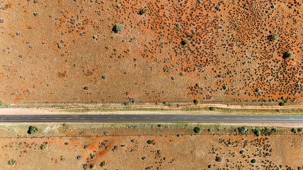 Aerial view of a long straight road cuts through the arid landscape contrasting the ochre earth with the grey asphalt Karoo Desert Northern Cape South Africa. Aerial view of a long straight road cuts through the arid landscape contrasting the ochre earth with the grey asphalt Karoo Desert Northern Cape South Africa.