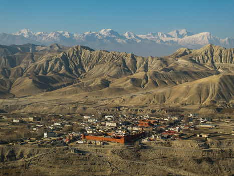 Aerial view of the historic Kag Chode Thupten Samphel Ling Monastery with red walls in Kagbeni surrounded by the arid landscape of the Mustang region and Himalayan peaks in Nepal.