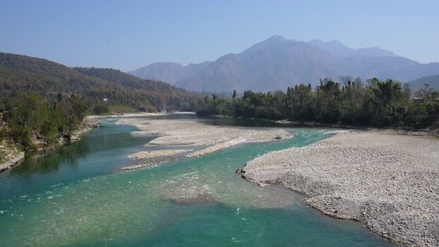 View of a wide turquoise river flowing through mountains Nepal.