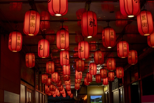 View of traditional red Chinese lanterns with black calligraphy hanging from a ceiling in a dimly lit urban setting in Beijing Beijing China. View of traditional red Chinese lanterns with black calligraphy hanging from a ceiling in a dimly lit urban setting in Beijing Beijing China.