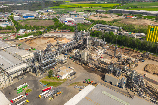 Aerial view of a large industrial wood processing plant with complex machinery silos and conveyor belts under a clear sky in Jihlava Vysocina Region Czechia.