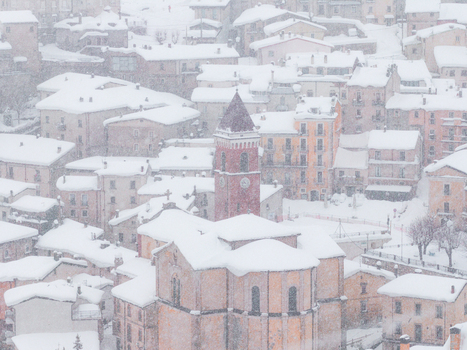 Aerial view of the historic town of Rivisondoli covered in heavy snow with a prominent church tower and stone buildings in Rivisondoli Abruzzo Italy.