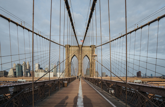View of the Brooklyn Bridge pedestrian walkway with its iconic suspension cables and the Manhattan skyline in the background New York New York United States.