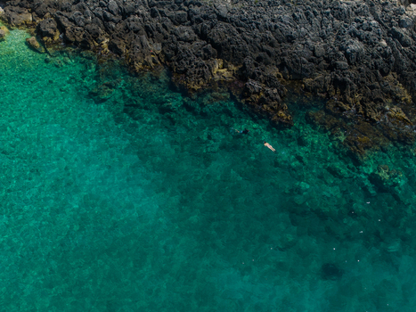 Aerial view of people swimming in crystal clear turquoise water along a rugged dark rocky coastline at Aquarium Beach Jala Vlore County Albania. Aerial view of people swimming in crystal clear turquoise water along a rugged dark rocky coastline at Aquarium Beach Jala Vlore County Albania.