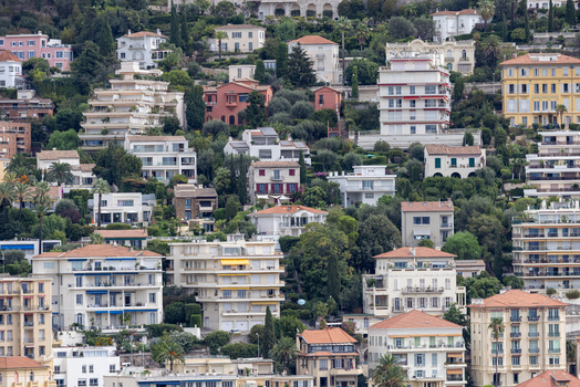 Aerial view of hillside residential area featuring dense Mediterranean architecture terracotta rooftops lush green trees and terraced buildings in Nice Provence Alpes Cote d Azur France. Aerial view of hillside residential area featuring dense Mediterranean architecture terracotta rooftops lush green trees and terraced buildings in Nice Provence Alpes Cote d Azur France.