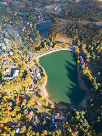 Aerial view of Velka Vindsachta and Evickino lakes surrounded by autumn forests and residential houses in Stiavnicke Bane Banskobystricky kraj Slovakia.