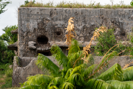 View of the historic North Field Base ruins featuring weathered concrete walls with exposed rebar surrounded by lush tropical vegetation in Northern Tinian Tinian Northern Mariana Islands. View of the historic North Field Base ruins featuring weathered concrete walls with exposed rebar surrounded by lush tropical vegetation in Northern Tinian Tinian Northern Mariana Islands.