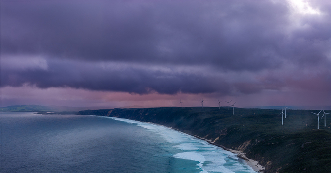 Aerial view of the Sandpatch wind farm with wind turbines situated on coastal cliffs above the Southern Ocean under dramatic storm clouds in Albany Western Australia Australia. Aerial view of the Sandpatch wind farm with wind turbines situated on coastal cliffs above the Southern Ocean under dramatic storm clouds in Albany Western Australia Australia.