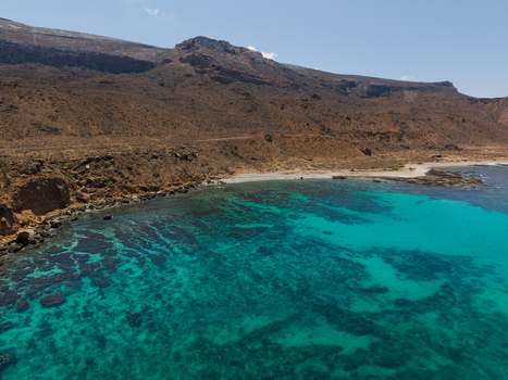 Aerial view of turquoise waters gently meet the rugged sun baked cliffs a stark contrast of vibrant blues and earthy browns Siqirah Socotra Yemen. Aerial view of turquoise waters gently meet the rugged sun baked cliffs a stark contrast of vibrant blues and earthy browns Siqirah Socotra Yemen.
