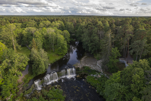 Aerial view of Keila Joa waterfall surrounded by lush green forest and trees under a cloudy sky in Keila Joa Harju County Estonia.