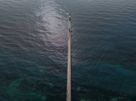 Aerial view of a long industrial pier extending into the deep blue Caribbean Sea in Bajos de Haina San Cristobal Province Dominican Republic.