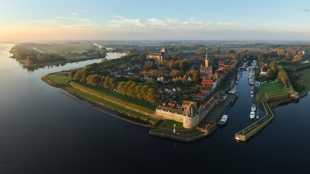 Aerial view of the historic town of Veere featuring the Grote Kerk and Campveerse Toren surrounded by water and green ramparts at sunset in Veere Zeeland Netherlands.