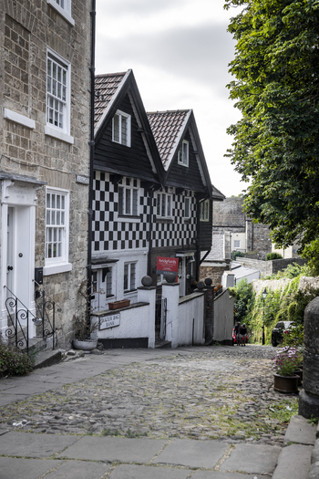 Knaresborough England United Kingdom 14 July 2026 View of historic timber framed houses with distinctive black and white checkered facades lining a steep cobblestone street.