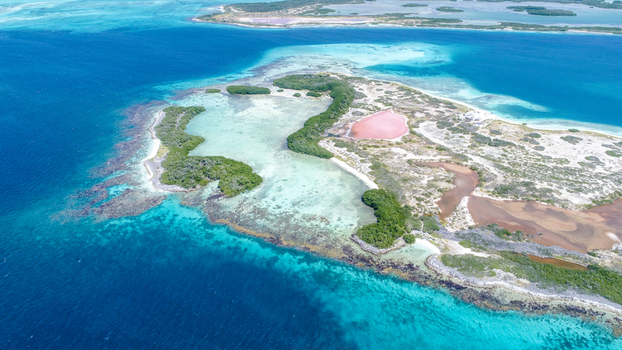 Aerial view of Los Roques archipelago featuring vibrant turquoise waters coral reefs mangrove islands and a distinct pink salt pond in Los Roques Dependencias Federales Venezuela. Aerial view of Los Roques archipelago featuring vibrant turquoise waters coral reefs mangrove islands and a distinct pink salt pond in Los Roques Dependencias Federales Venezuela.