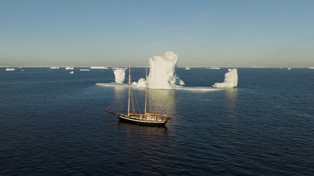 Aerial view of sailboat near arch iceberg Greenland. Aerial view of sailboat near arch iceberg Greenland.
