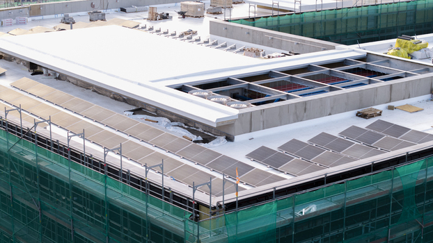 Aerial view of an AI data center under construction featuring solar panels and HVAC units on the roof surrounded by green safety netting in Krakow Lesser Poland Voivode Poland. Aerial view of an AI data center under construction featuring solar panels and HVAC units on the roof surrounded by green safety netting in Krakow Lesser Poland Voivode Poland.