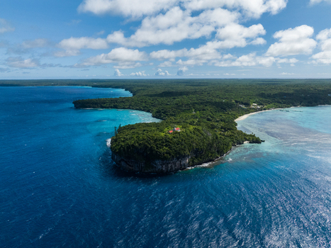 Aerial view of the vibrant turquoise waters meeting the lush dense forest on the coastal cliffs a tropical paradise from above Lifou New Caledonia. Aerial view of the vibrant turquoise waters meeting the lush dense forest on the coastal cliffs a tropical paradise from above Lifou New Caledonia.