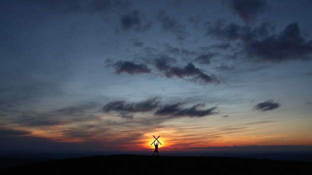 View of a person silhouetted against a vibrant sunset holding skis in an X shape on the summit of Colomby de Gex with dramatic clouds Echenevex Auvergne Rhone Alpes France. View of a person silhouetted against a vibrant sunset holding skis in an X shape on the summit of Colomby de Gex with dramatic clouds Echenevex Auvergne Rhone Alpes France.