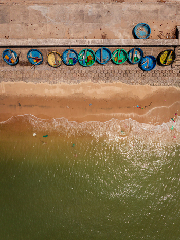 Aerial view of traditional round basket boats lined up along a sandy beach with gentle waves washing onto the shore in Vietnam. Aerial view of traditional round basket boats lined up along a sandy beach with gentle waves washing onto the shore in Vietnam.