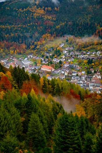 View of a small town nestled in a valley surrounded by the colorful autumn foliage of the Black Forest with mist rising from the trees Offenburg Baden Wurttemberg Germany. View of a small town nestled in a valley surrounded by the colorful autumn foliage of the Black Forest with mist rising from the trees Offenburg Baden Wurttemberg Germany.