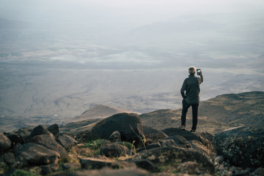 Turkey 14 August 2023 View of a person standing on the rocky slopes of Mount Ararat capturing a photograph of the vast hazy mountain landscape with a smartphone. Turkey 14 August 2023 View of a person standing on the rocky slopes of Mount Ararat capturing a photograph of the vast hazy mountain landscape with a smartphone.