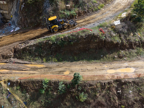 Aerial view of a yellow backhoe loader working on a muddy construction site with tire tracks and orange safety fencing Istanbul Istanbul Turkiye. Aerial view of a yellow backhoe loader working on a muddy construction site with tire tracks and orange safety fencing Istanbul Istanbul Turkiye.