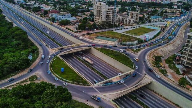Aerial view of a busy highway interchange with multi lane roads circular ramps and surrounding urban infrastructure in Ghana. Aerial view of a busy highway interchange with multi lane roads circular ramps and surrounding urban infrastructure in Ghana.