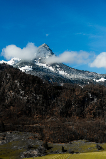 View of snow dusted mountain peaks rise majestically against a clear blue sky a picturesque panorama unfolding from a train window Train from Lucerne to Interlaken Switzerland. View of snow dusted mountain peaks rise majestically against a clear blue sky a picturesque panorama unfolding from a train window Train from Lucerne to Interlaken Switzerland.