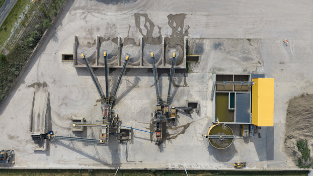 Aerial view of a gravel and sand processing plant with conveyor belts aggregate piles and water treatment tanks in La Longueville Hauts de France France.