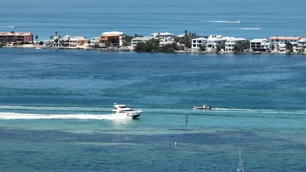 Aerial view of boats cruising in the turquoise waters near the coastal village of Cortez with residential buildings and palm trees along the shoreline in Cortez Florida United States. Aerial view of boats cruising in the turquoise waters near the coastal village of Cortez with residential buildings and palm trees along the shoreline in Cortez Florida United States.