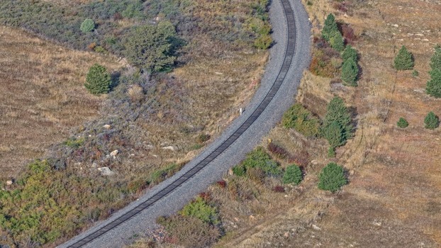 Aerial view of a railway track curving through a grassy landscape with scattered trees in Golden Colorado United States.