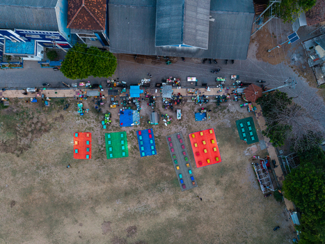 Aerial view of Karimunjawa Town Square with colorful mats and market stalls arranged on the ground surrounded by buildings and trees in Karimunjawa Central Java Indonesia. Aerial view of Karimunjawa Town Square with colorful mats and market stalls arranged on the ground surrounded by buildings and trees in Karimunjawa Central Java Indonesia.