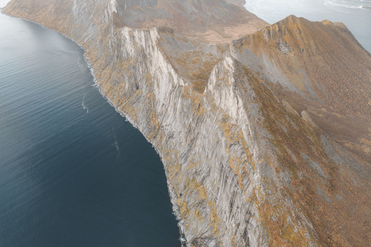 Aerial view of the dramatic coastal mountain peaks of Senja rising above the deep blue waters of the Norwegian Sea in Senja Troms Norway.