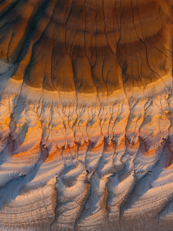 Aerial view of eroded clay formations with intricate rills and gullies in shades of brown orange and white in Mangystau Region Kazakhstan. Aerial view of eroded clay formations with intricate rills and gullies in shades of brown orange and white in Mangystau Region Kazakhstan.