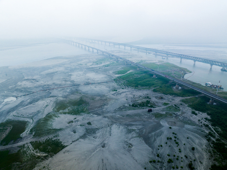 Aerial view of the long Bangabandhu Bridge spanning across the wide Jamuna River with sandy riverbanks under a misty sky in Tangail Dhaka Division Bangladesh. Aerial view of the long Bangabandhu Bridge spanning across the wide Jamuna River with sandy riverbanks under a misty sky in Tangail Dhaka Division Bangladesh.