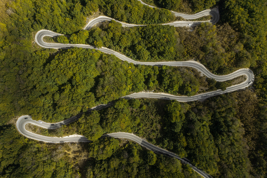 Aerial view of a winding mountain road snaking through a dense green forest with sharp hairpin turns and lush vegetation in Savnik Savnik Municipality Montenegro. Aerial view of a winding mountain road snaking through a dense green forest with sharp hairpin turns and lush vegetation in Savnik Savnik Municipality Montenegro.