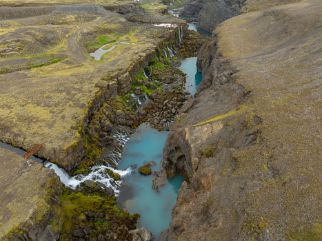 Aerial view of Sigoldugljufur canyon featuring turquoise water cascading waterfalls and moss covered volcanic rock formations in Rangarthing ytra Iceland. Aerial view of Sigoldugljufur canyon featuring turquoise water cascading waterfalls and moss covered volcanic rock formations in Rangarthing ytra Iceland.