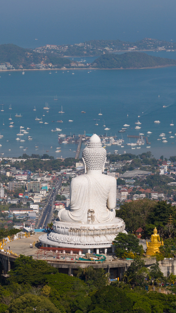 Aerial view of Big Buddha Phuket overlooking the coastal town and turquoise bay filled with boats under a clear blue sky Karon Phuket Thailand. Aerial view of Big Buddha Phuket overlooking the coastal town and turquoise bay filled with boats under a clear blue sky Karon Phuket Thailand.