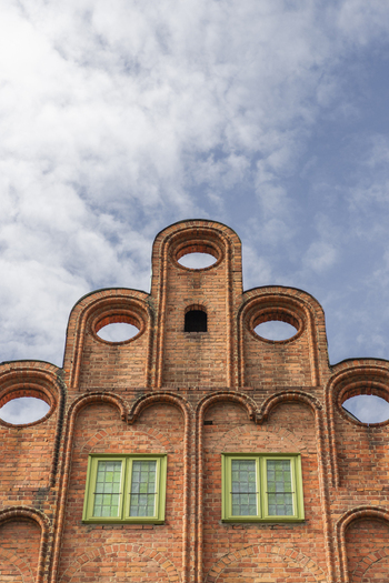 Gdansk Poland 07 September 2026 View of the ornate red brick stepped gable with circular openings and green windows against a blue sky. Gdansk Poland 07 September 2026 View of the ornate red brick stepped gable with circular openings and green windows against a blue sky.
