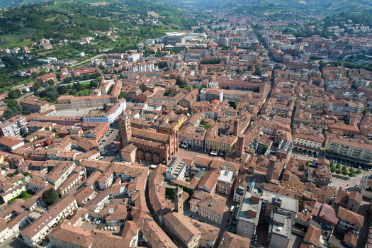 Aerial view of the historic center of Alba featuring the red tiled rooftops and the majestic Alba Cathedral under a clear sky in Alba Piedmont Italy.