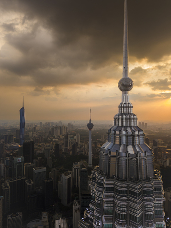 Kuala Lumpur Malaysia 11 March 2026 Aerial view of the Petronas Twin Towers spire and KL Tower under a dramatic sunset sky with storm clouds.