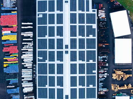 Aerial view of an industrial facility featuring a large roof covered in solar panels surrounded by organized storage areas with colorful pipes and industrial components in Jelgava Latvia. Aerial view of an industrial facility featuring a large roof covered in solar panels surrounded by organized storage areas with colorful pipes and industrial components in Jelgava Latvia.