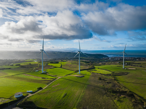 Aerial view of wind turbines standing on lush green fields under a cloudy sky with the Atlantic coastline in the distance Ribamar Portugal. Aerial view of wind turbines standing on lush green fields under a cloudy sky with the Atlantic coastline in the distance Ribamar Portugal.