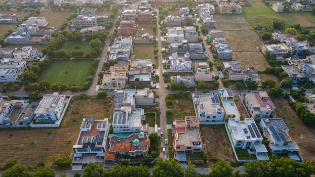 Aerial view of a residential neighborhood featuring houses with solar panels on rooftops green lawns and tree lined streets in Lahore Punjab Pakistan.