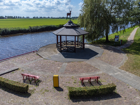 Aerial view of a charming gazebo with a deer weather vane nestled beside a tranquil canal with vibrant green fields in the distance Tollebeek Flevoland Netherlands.